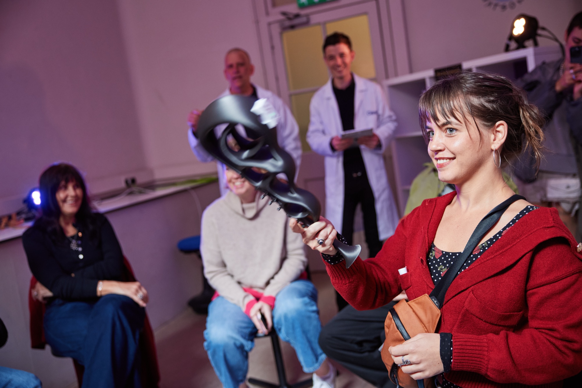 A participant holding an instrument in front of a seated group